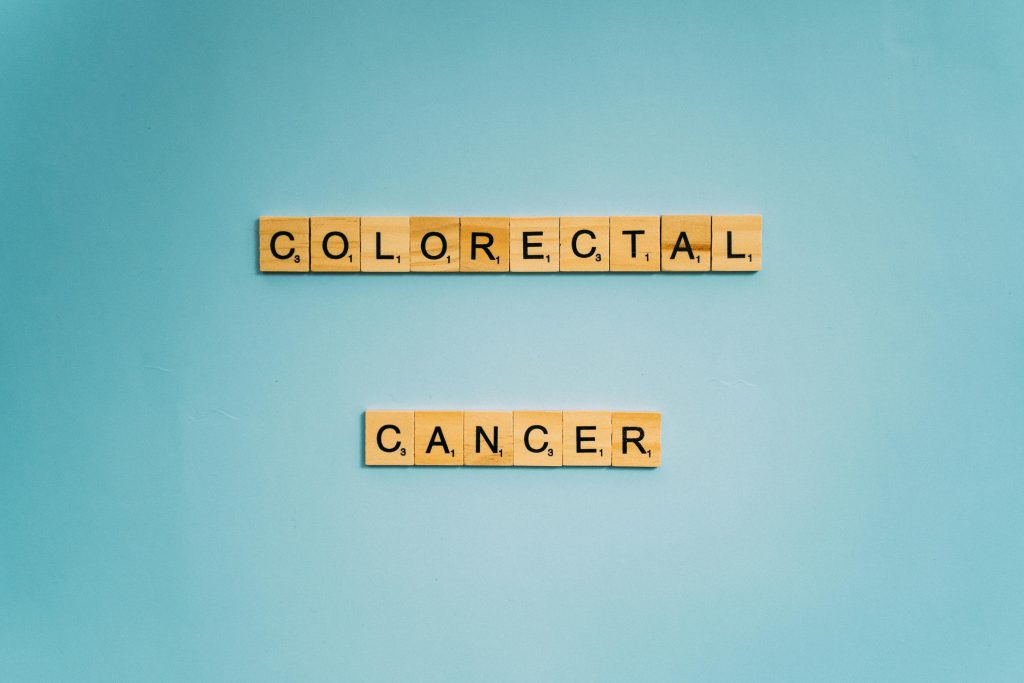 Scrabble tiles spell 'Colorectal Cancer' on a light blue background for cancer awareness.